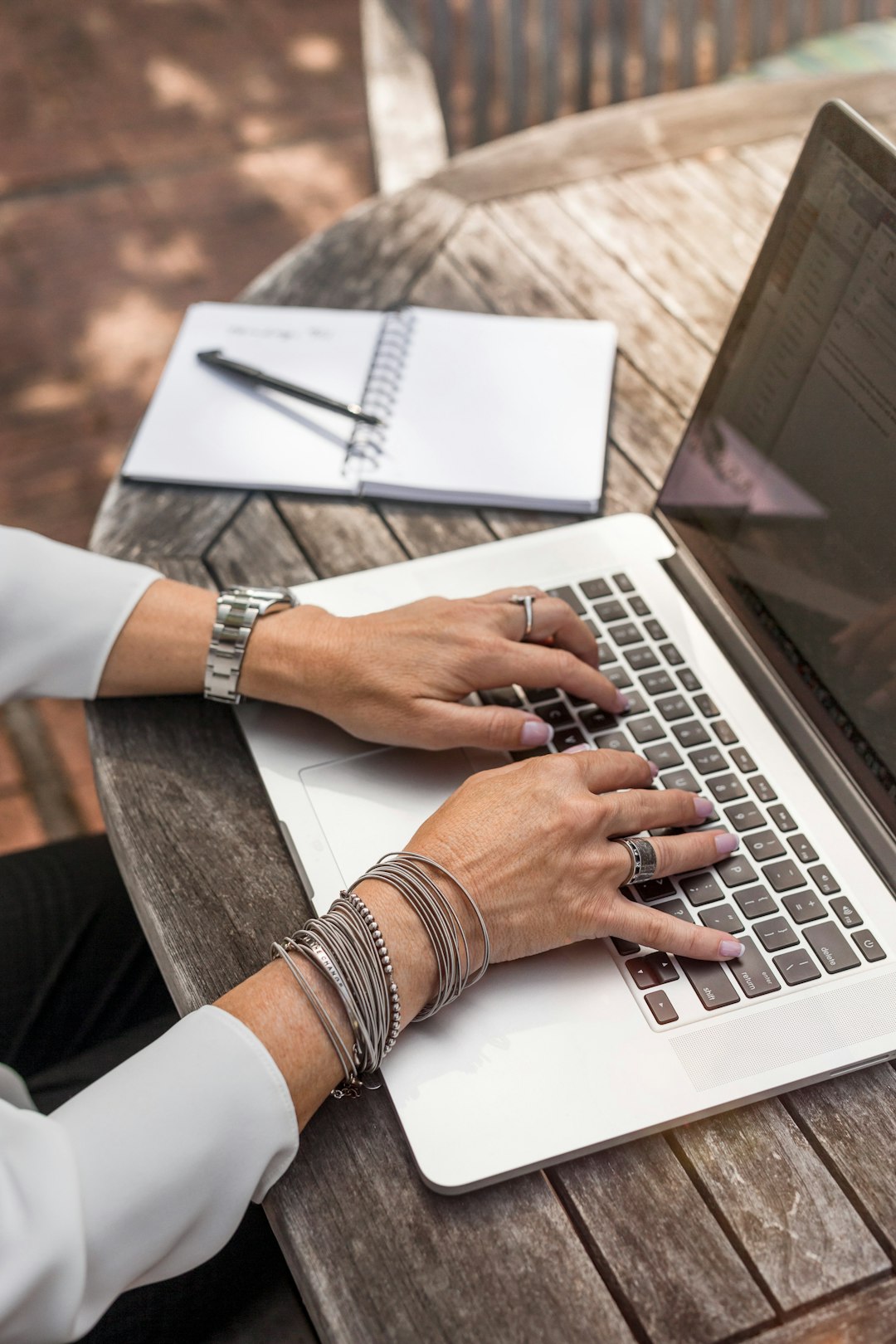 person typing on macbook pro on brown wooden table during daytime photo 0qvtyp0gh3a Contact