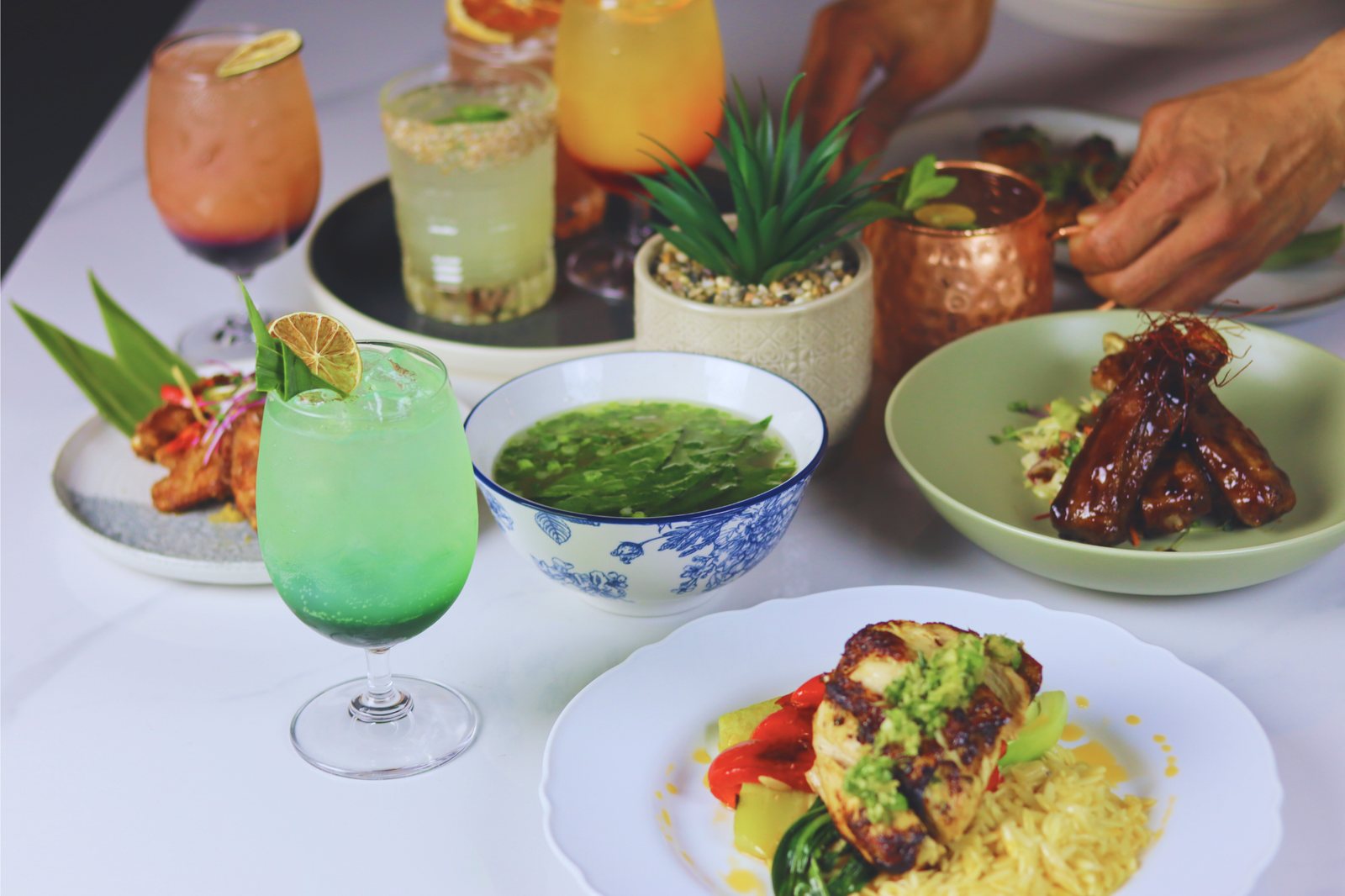 halina cocktails and shared plates HALINÁ Modern Filipino Kitchen + Bar A spread of Halina cocktails and shared Filipino plates on a white table